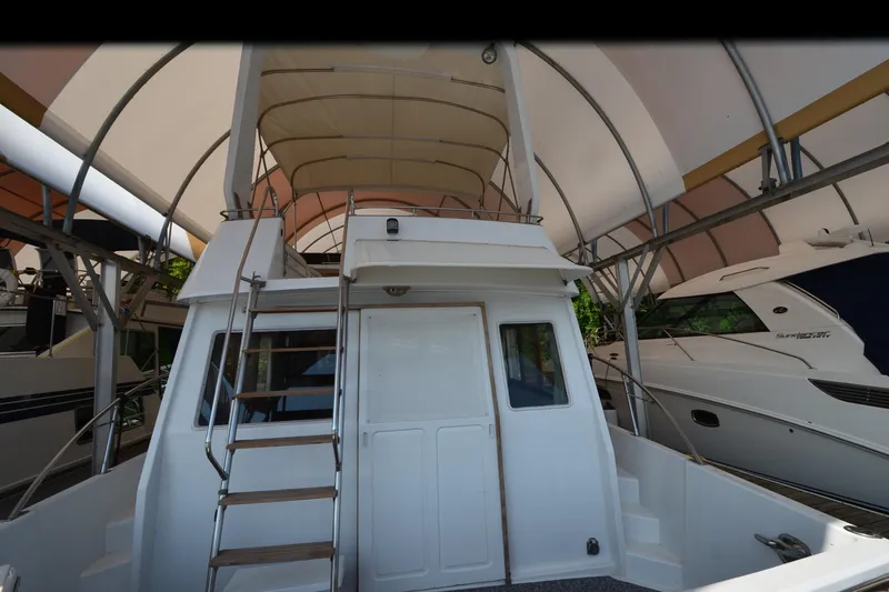 Slide: The Image of 1985 Kha Shing 40 yacht under canopy, featuring rear view with ladder and covered deck. - 10
