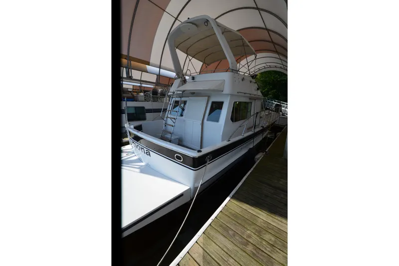 Slide: The Image of 1985 Kha Shing 40 yacht docked under canopy, showcasing sleek design and spacious deck. - 2