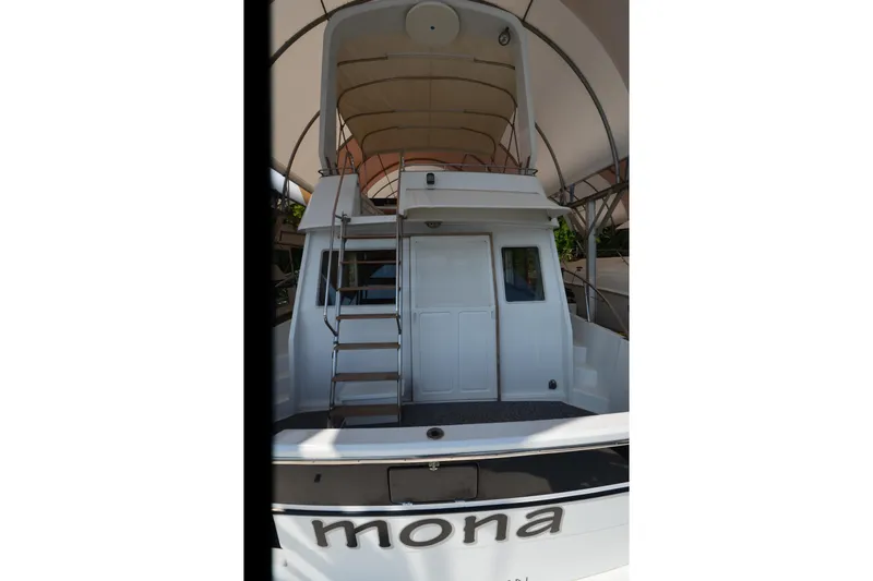 Slide: The Image of 1985 Kha Shing 40 yacht, rear view with ladder and canopy, named "Mona". - 9