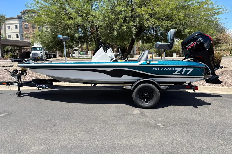 The Image of 2027 Nitro Z17 fishing boat on trailer, parked outdoors under a tree. - 0