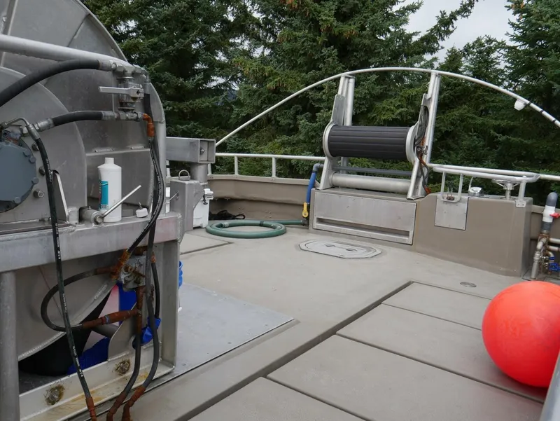 Slide: The Image of The deck of a 2022 Custom Freestyle Marine 32 boat with equipment and trees in the background. - 27