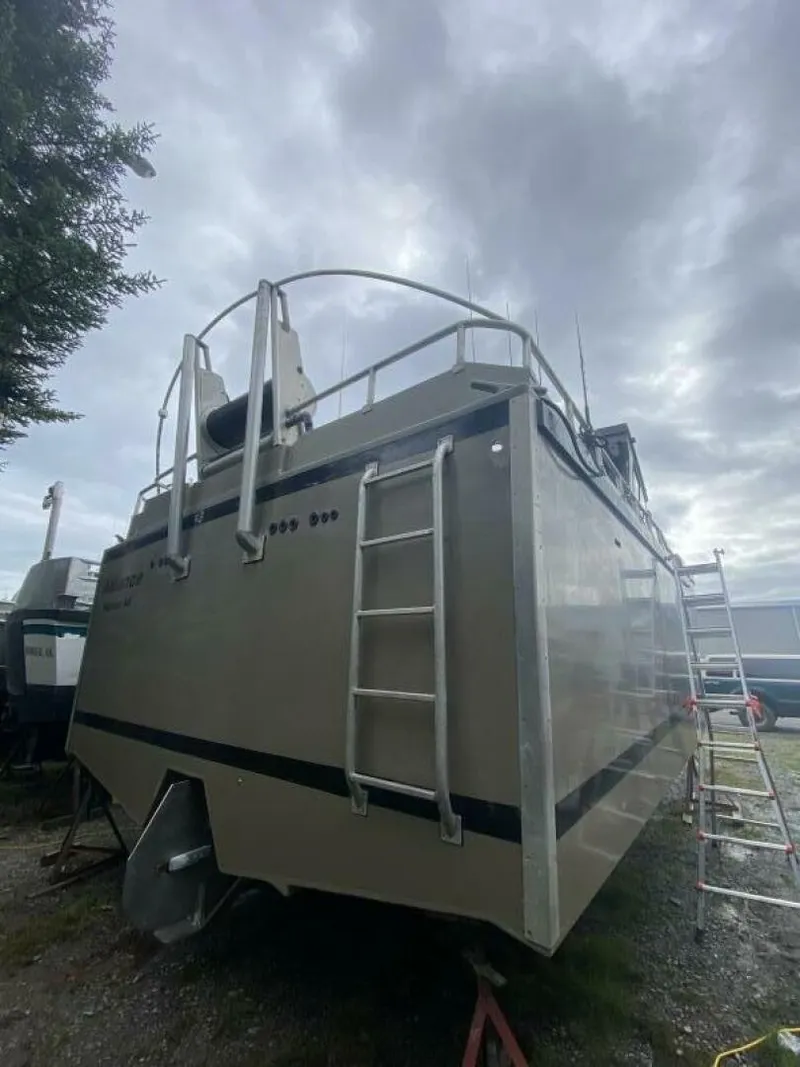 Slide: The Image of A modern boat with an aluminum hull and stern ladder sits in dry dock under a cloudy sky. - 36