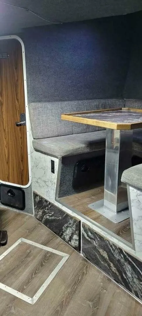 Slide: The Image of The image shows a boat interior with a cozy seating area and wooden table. - 24