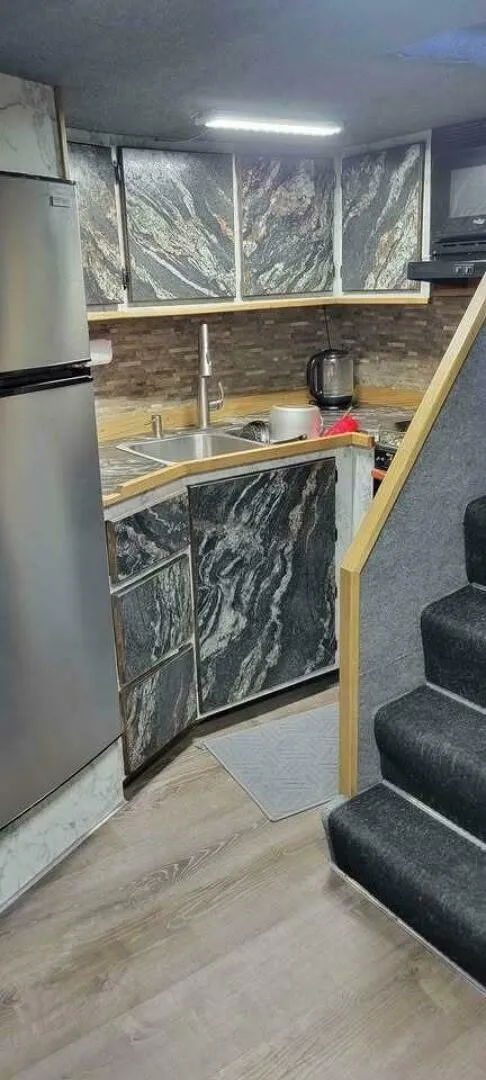 Slide: The Image of A boat's kitchen with modern appliances, marble-patterned cabinets, and a staircase. - 13