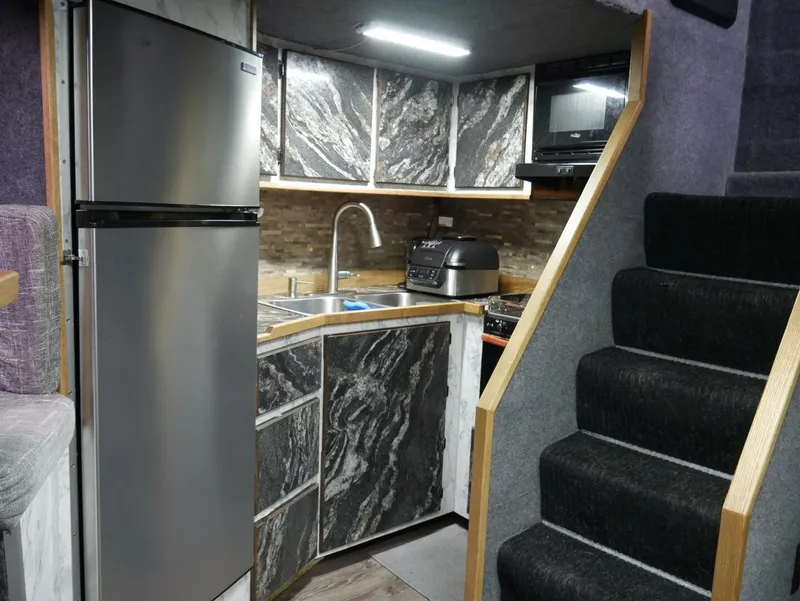 Slide: The Image of A boat's kitchen with a fridge, sink, and microwave. Modern design with stairs beside it. - 33