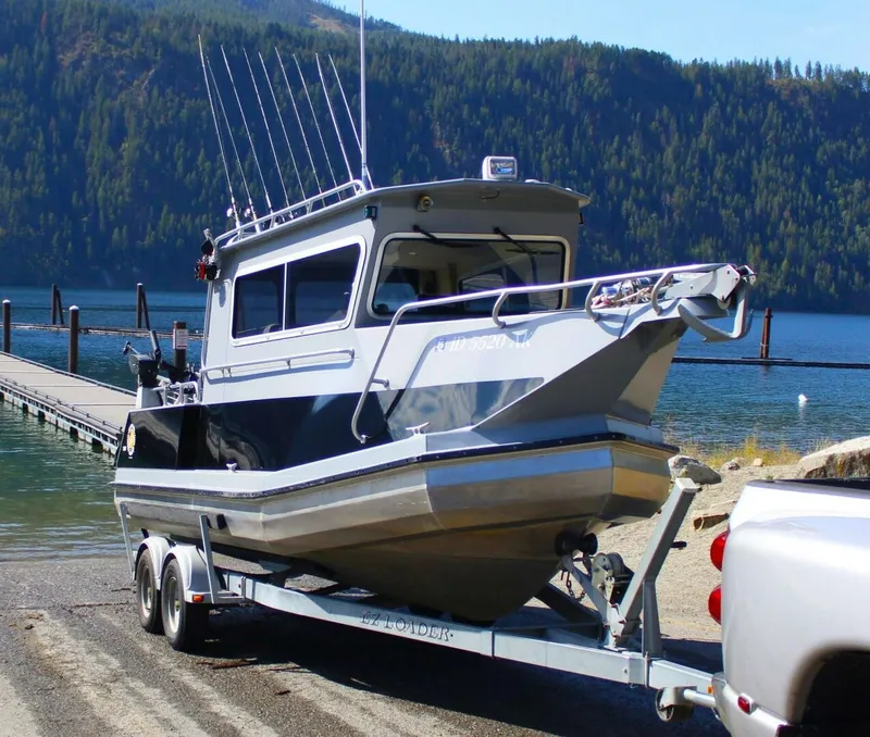 Slide: The Image of A silver boat on a trailer by a lakeside, surrounded by wooded hills. - 7