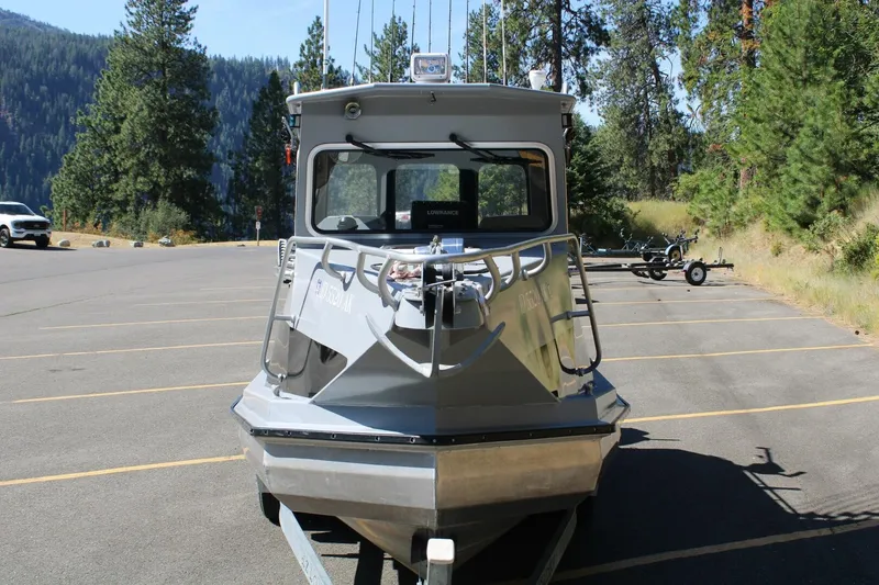 Slide: The Image of A gray boat on a trailer in a wooded parking area. - 5