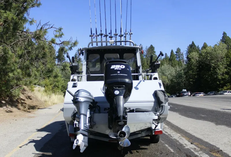 Slide: The Image of A 2005 ACB 27 boat with multiple fishing rods and two outboard motors, parked on a road. - 4