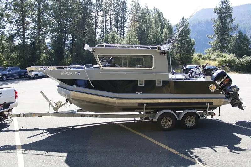 Slide: The Image of A 2005 ACB 27 boat on a trailer, surrounded by trees and mountains. - 12