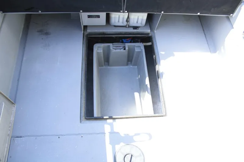 Slide: The Image of An open storage compartment on a boat with a gray floor and black cover. - 26
