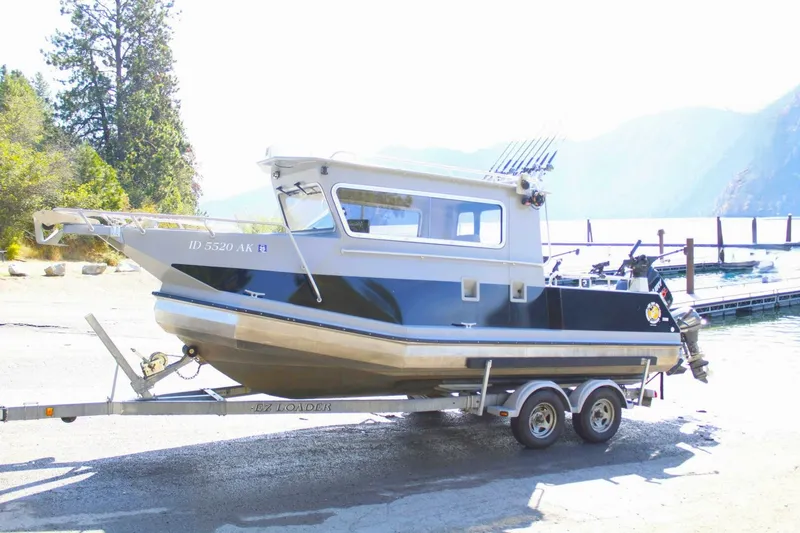 Slide: The Image of A 2005 ACB 27 boat on a trailer, near a lake with trees in the background. - 3