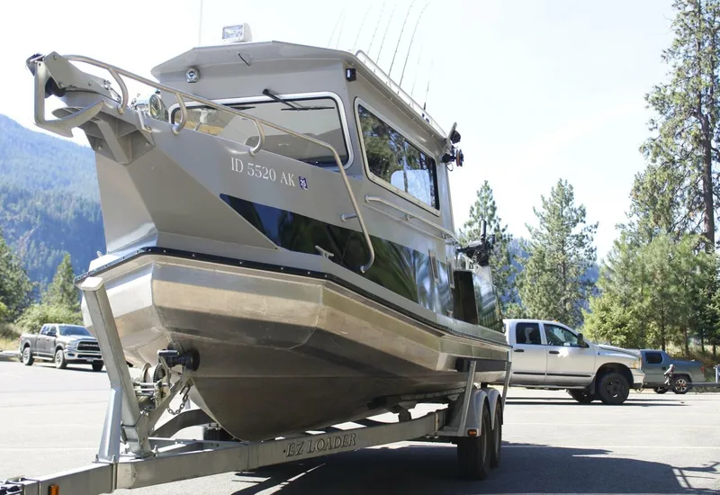 Slide: The Image of A 2005 ACB 27 boat on a trailer, surrounded by trees and mountains. - 15