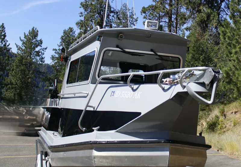 Slide: The Image of A gray cabin boat on a trailer, surrounded by trees. - 10