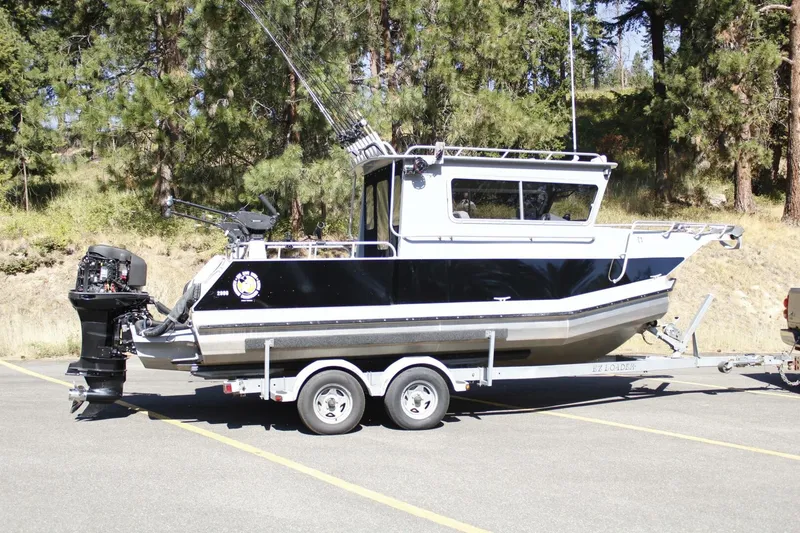 Slide: The Image of A black and silver boat on a trailer, surrounded by trees and a parking lot. - 24