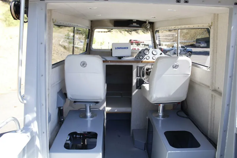 Slide: The Image of Interior of a 2005 ACB 27 boat with two white seats and a helm station. - 40