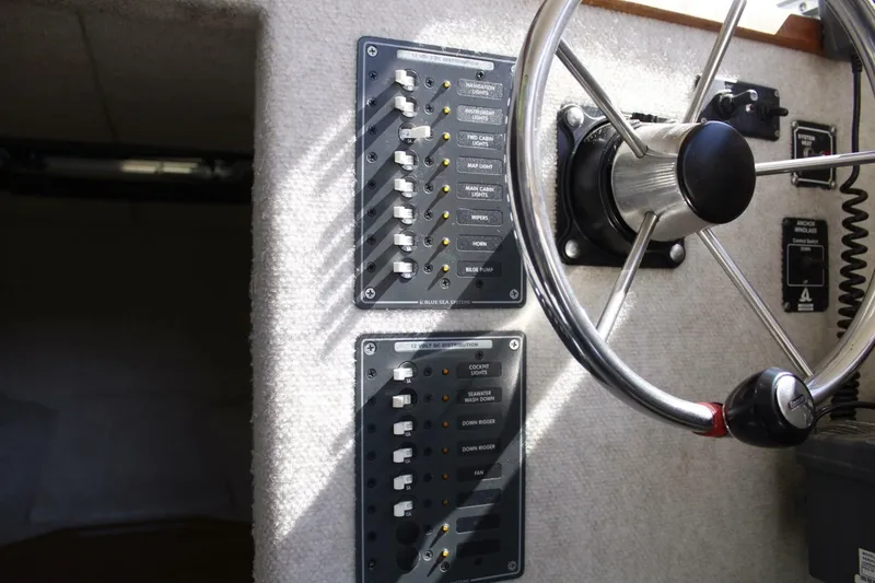 Slide: The Image of The image shows a boat's helm with switches and a steering wheel. - 47