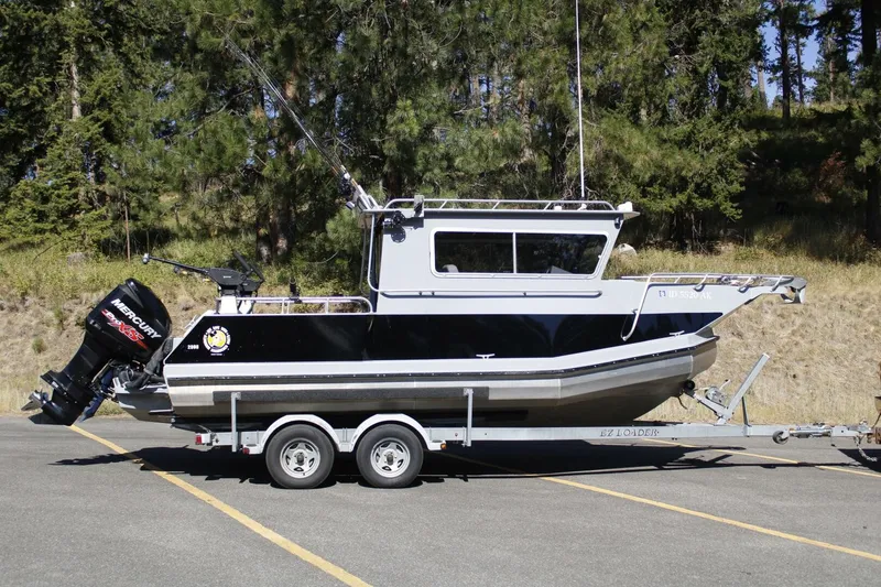 Slide: The Image of A black boat on a trailer surrounded by trees. It features an outboard motor and a cabin. - 9