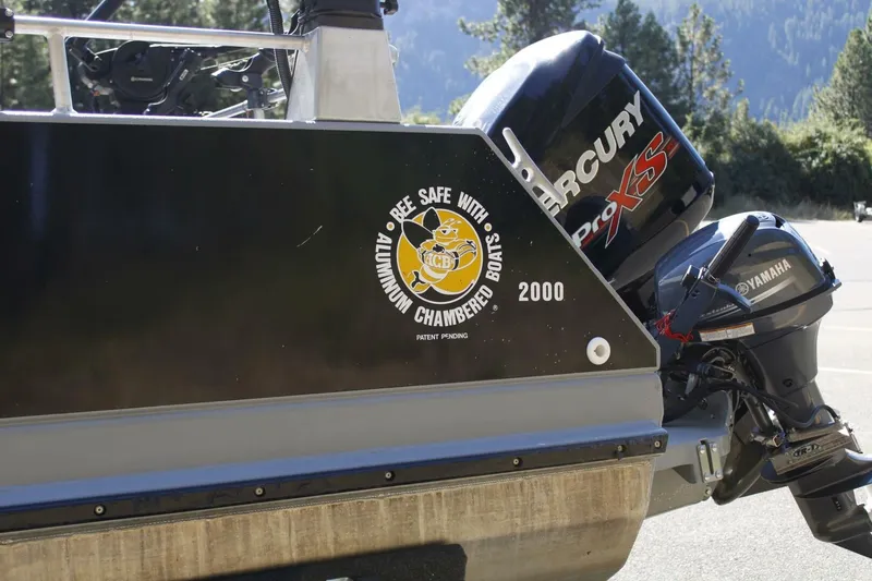 Slide: The Image of An aluminum boat with a Mercury engine, parked on a trailer in a mountainous area. - 16