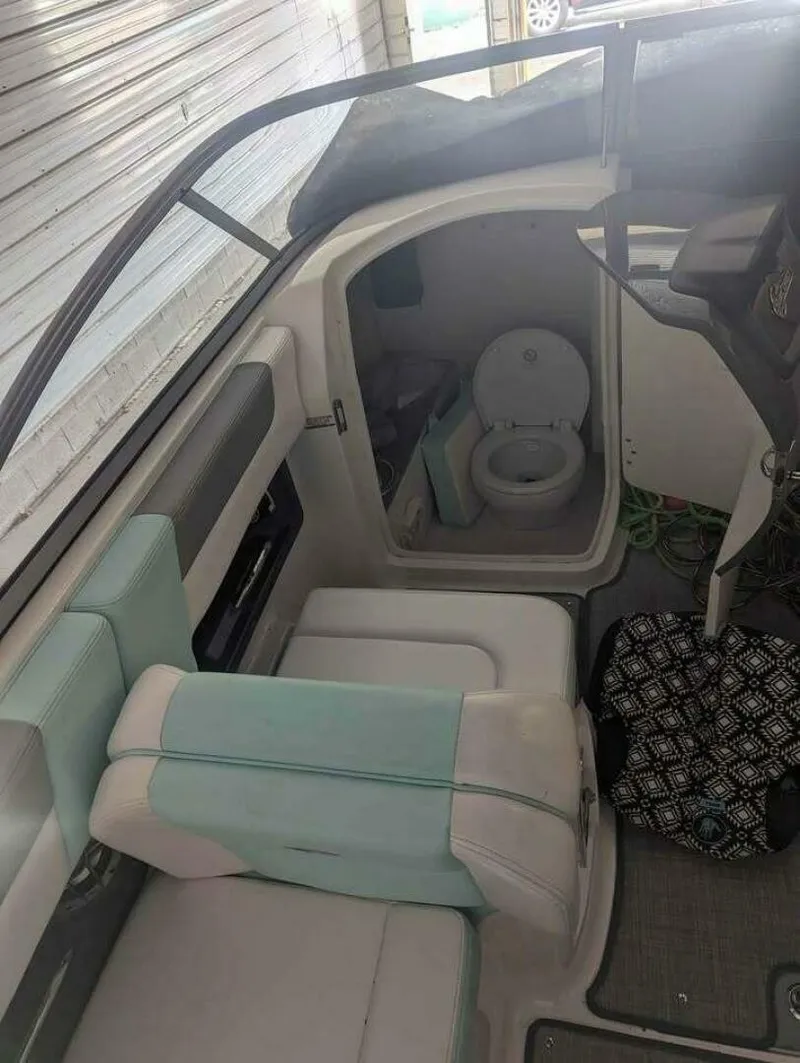 Slide: The Image of The image shows the interior of a 2021 Chaparral 230 Suncoast boat. There are seats and a small toilet. - 5