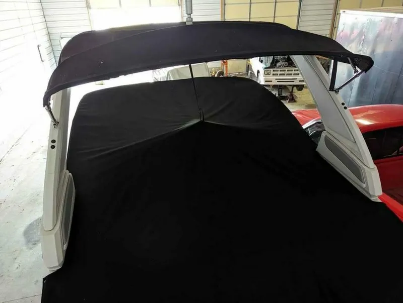 Slide: The Image of The image shows a 2021 Chaparral 230 Suncoast boat with a black cover in a storage facility. - 13