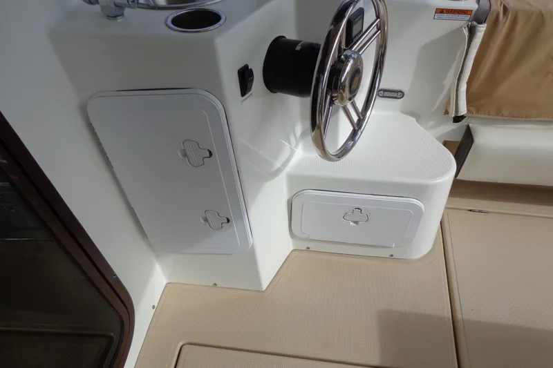 Slide: The Image of 2016 Ranger Tugs R-31 S helm station with steering wheel and storage compartments. - 12