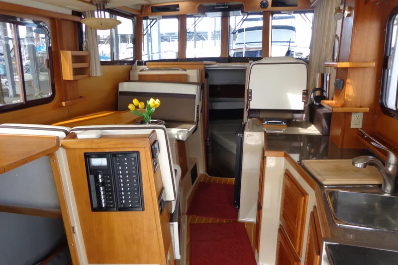 Slide: The Image of Interior of 2016 Ranger Tugs R-31 S, featuring wood finishes and a cozy dining area. - 13