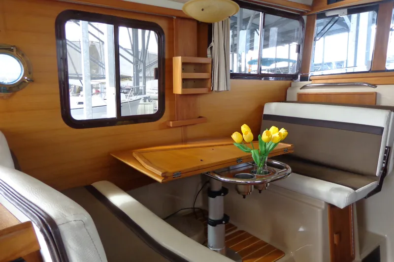 Slide: The Image of Interior of 2016 Ranger Tugs R-31 S with wooden table, seating, and yellow tulips. - 15