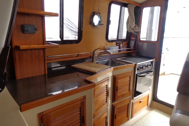 Slide: The Image of 2016 Ranger Tugs R-31 S interior kitchen with wooden cabinets and modern appliances. - 17