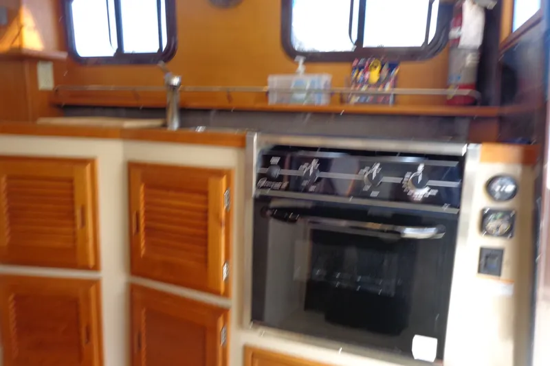 Slide: The Image of Interior of 2016 Ranger Tugs R-31 S with wooden cabinets and a built-in oven. - 34