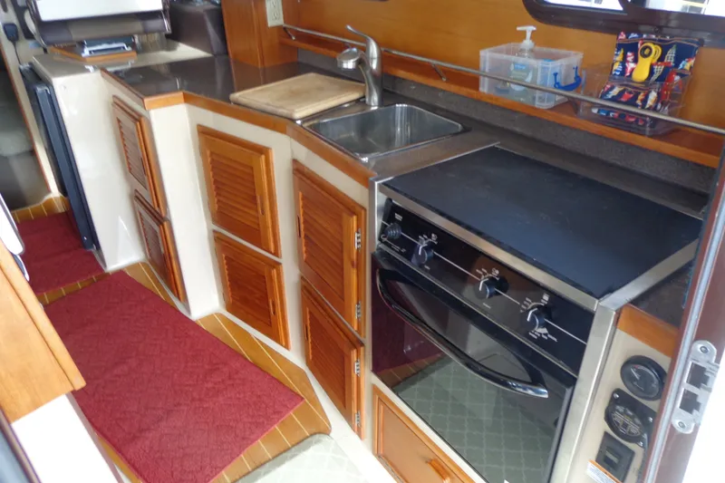 Slide: The Image of Compact kitchen in 2016 Ranger Tugs R-31 S boat with stove, sink, and wooden cabinets. - 14
