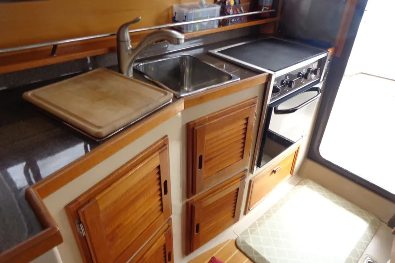 Slide: The Image of 2016 Ranger Tugs R-31 S galley with sink, stove, and wooden cabinetry. - 18