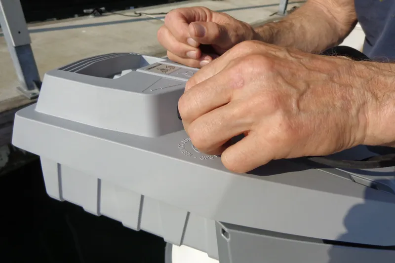 Slide: The Image of Hands working on a gray device aboard a 2016 Ranger Tugs R-31 S boat. - 58