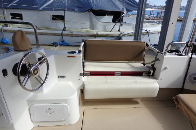 Slide: The Image of 2016 Ranger Tugs R-31 S cockpit with steering wheel and seating, docked by a marina. - 38