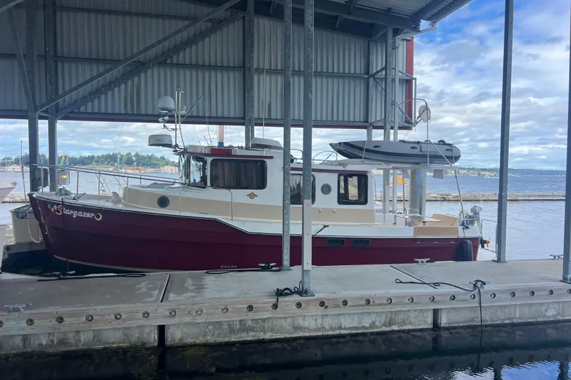 The Image of 2016 Ranger Tugs R-31 S docked under a covered marina with scenic waterfront view. - 1