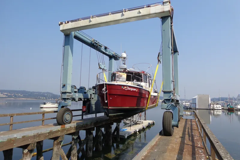 Slide: The Image of 2016 Ranger Tugs R-31 S boat lifted by a marina crane over calm waters. - 72