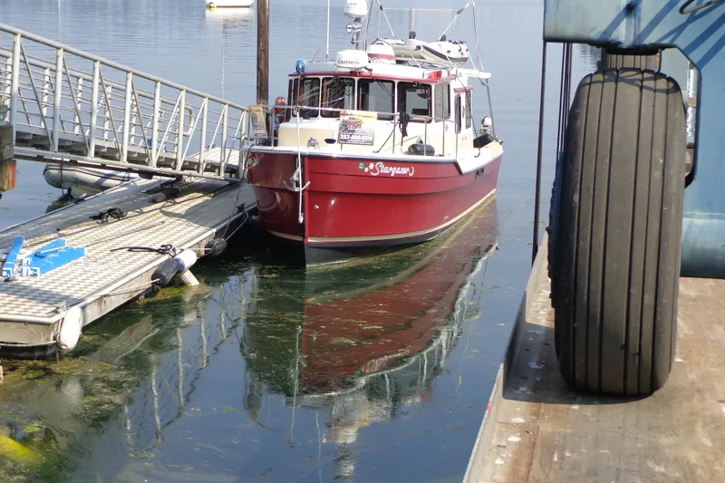 Slide: The Image of 2016 Ranger Tugs R-31 S docked at a marina, reflecting on calm water. - 69