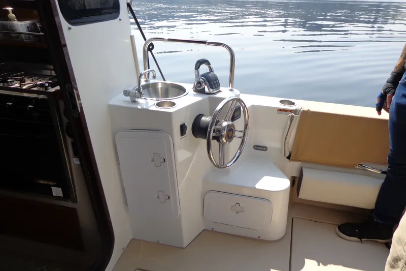 Slide: The Image of 2016 Ranger Tugs R-31 S helm with sink and seating, docked on calm water. - 54