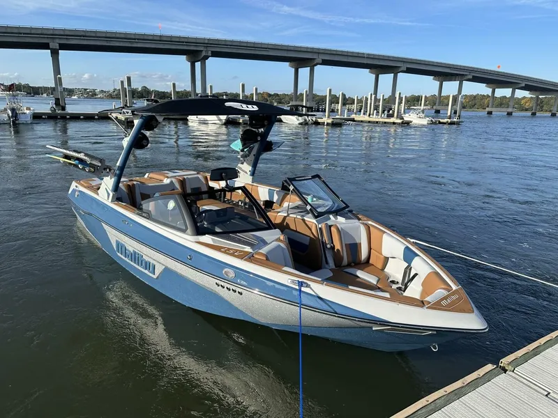 Slide: The Image of A 2023 Malibu Wakesetter 23 LSV docked. It features a blue and white design with modern interior. - 0