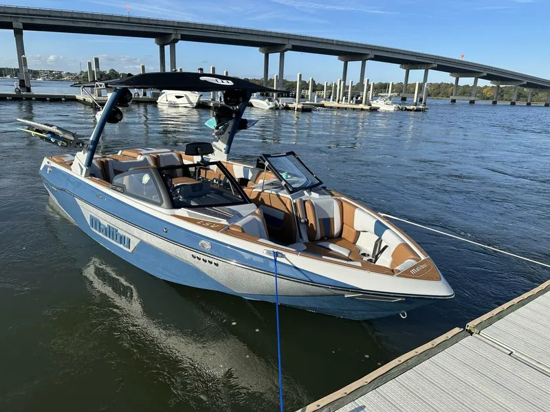 Slide: The Image of A 2023 Malibu Wakesetter 23 LSV docked. It features a sleek design with blue and white colors. - 11