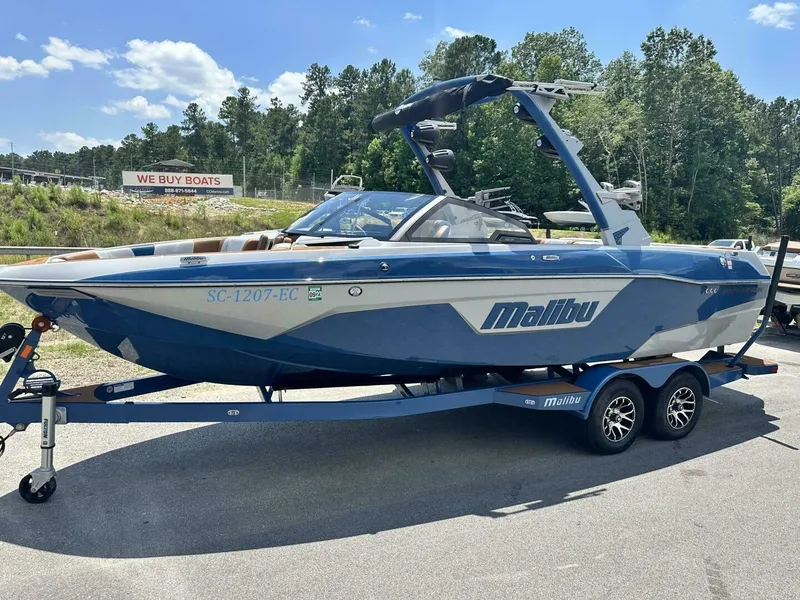 Slide: The Image of A 2023 Malibu Wakesetter 23 LSV on a trailer, surrounded by trees and a sign in the background. - 1