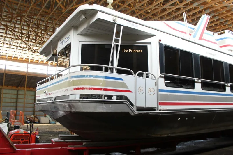 Slide: The Image of A 2000 Sumerset 75 Houston houseboat in a storage facility. It features colorful stripes and the name "The Princess." - 15