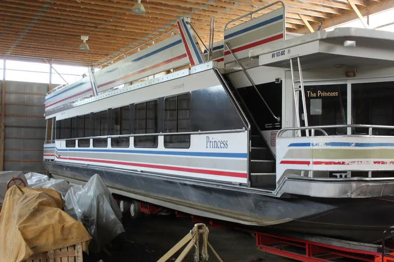 Slide: The Image of A 2000 Sumerset 75 Houston houseboat in a storage facility, featuring colorful stripes and "Princess" lettering. - 8
