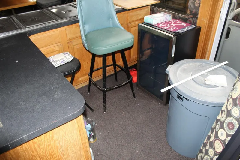 Slide: The Image of The interior of a houseboat with a kitchenette, bar stool, and small refrigerator. - 39