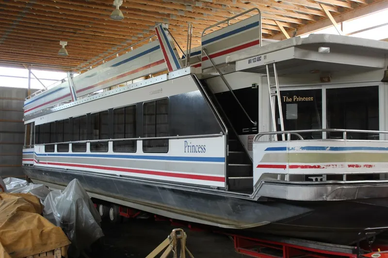 Slide: The Image of A 2000 Sumerset 75 Houston houseboat is in a warehouse. It features colorful stripes. - 13