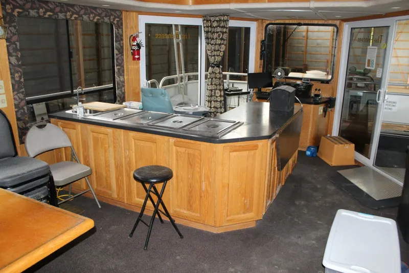 Slide: The Image of The interior view shows a kitchen with wooden cabinets and a bar counter on a houseboat. - 42