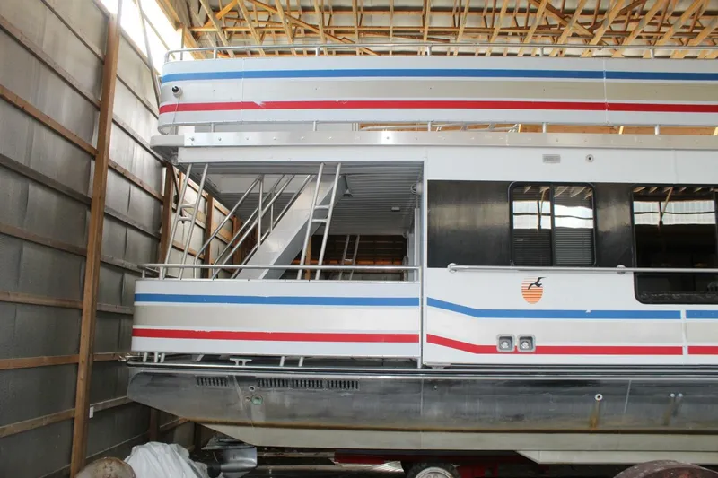 Slide: The Image of A 2000 Sumerset 75 Houston houseboat in a warehouse. It features a two-story design with colorful stripes. - 6