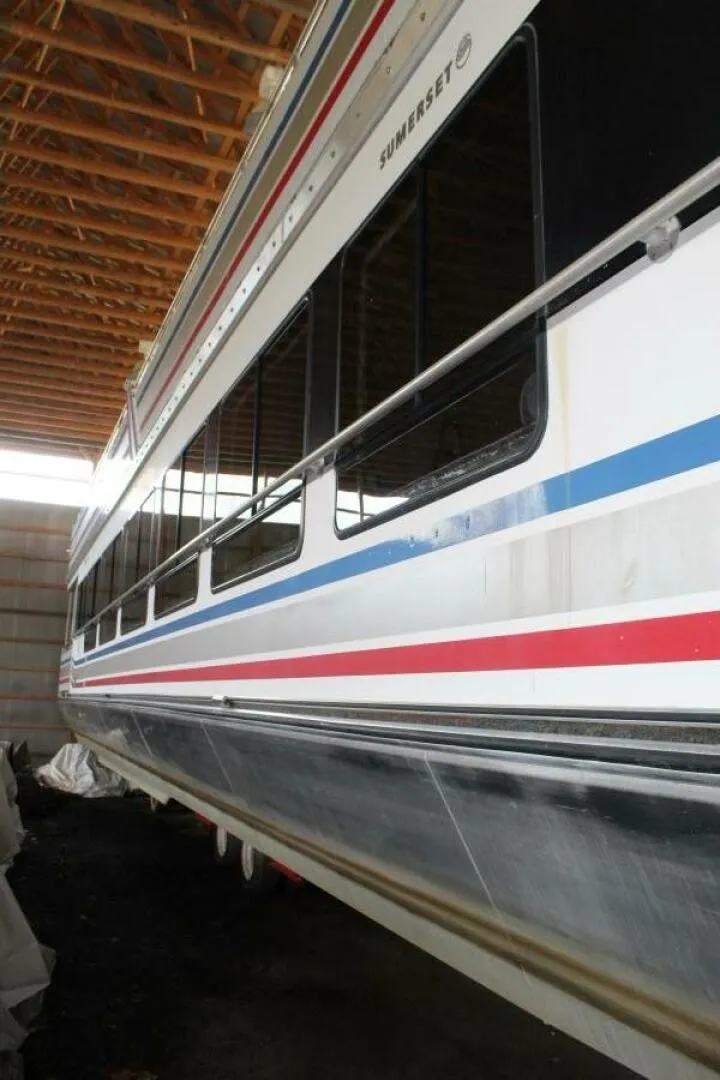 Slide: The Image of A 2000 Sumerset 75 Houston houseboat in a warehouse. It features a distinctive stripe design. - 11