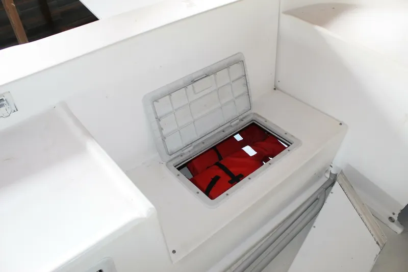 Slide: The Image of A white storage compartment on a boat with an open lid reveals orange life jackets. - 48