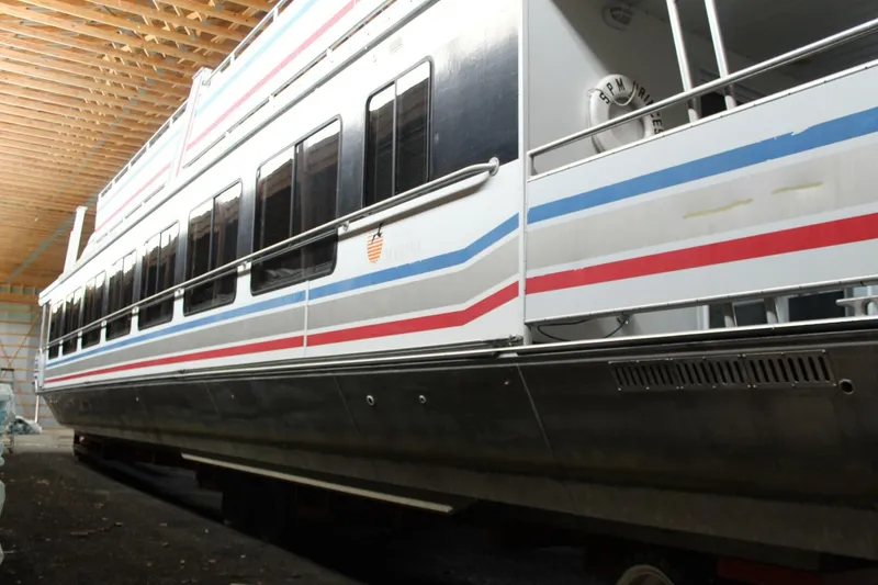 Slide: The Image of A 2000 Sumerset 75 Houston houseboat in a warehouse, featuring distinctive stripes and windows. - 2