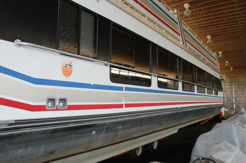 Slide: The Image of A 2000 Sumerset 75 Houston houseboat in a storage facility, featuring distinctive stripes. - 4